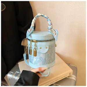 Dettaglio borsa a secchiello azzurra con tessuto in pizzo e manico a foulard moda