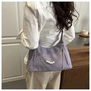 Detalle de bolso de hombro lila con cadenas metálicas decorativas y elegantes perlas blancas