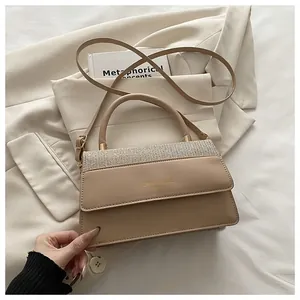 Detail of beige rectangular handbag featuring glitter paneling and gold hardware buckle