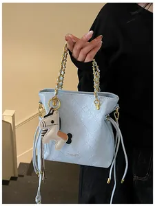 Detail of light blue quilted bucket bag with gold chain strap and pony charm