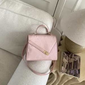 Detail of light pink crossbody bag with pleated texture and golden metal twist lock