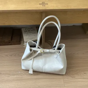 Close-up of ivory tote bag featuring gold D-ring detail and premium textured synthetic leather