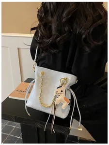 Detail of light blue bucket bag with quilted patterns, gold chains and pony charm