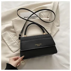 Detail of black handbag showing glitter texture contrast and gold logo on front