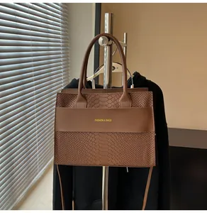 Dettaglio macro della borsa in pelle marrone coccodrillo con scritta Fashion & Bags