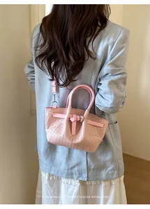 Pink woven bucket bag shown from behind on a model wearing a light blue blazer
