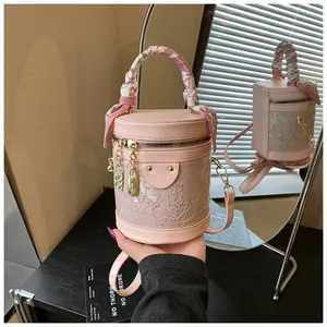 Dettaglio borsa a secchiello rosa con pizzo floreale bianco e manico in foulard di seta
