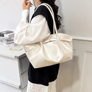 Sac seau crème élégant avec détail de sangle et boucle dorée porté par un mannequin