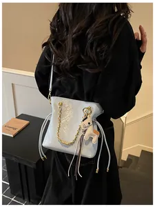 Close-up of light blue quilted bucket bag with gold chain and cute horse charm detail