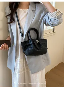 Detail of black woven texture shoulder bag with top handles and adjustable strap