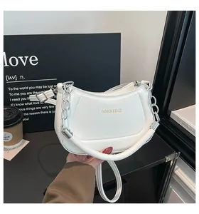 Nahaufnahme der weißen Halbmond-Stepptasche aus Leder mit goldener Mode-Schrift