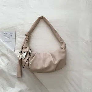 Detail der beigen New-Moon-Tasche mit vertikalen Falten und dekorativem Pferdeanhänger