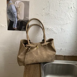 Detailed close-up of brown vintage tote bag with retro matte texture and gold buckle