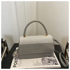 Detailed shot of grey leather handbag with rhinestone embellishment and shoulder strap