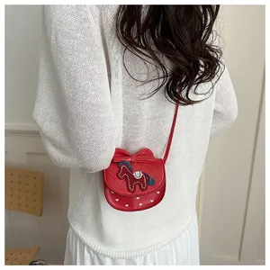 Detail van rode crossbodytas met strik, paardenborduursel en hartjesprint