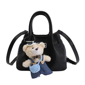 Black PU leather bucket bag for women with a cute teddy bear charm and crossbody strap