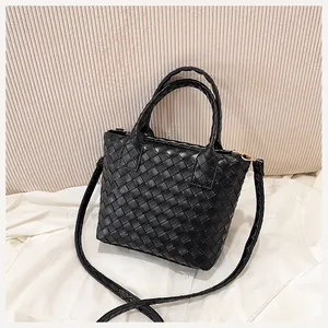 Detail of black woven leather bucket bag featuring gold metal hardware and smooth texture