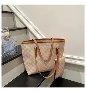 Detail view of large tote bag with matching mini pouch in logo print and brown leather trim