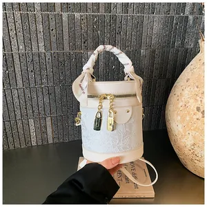 Dettaglio borsa a secchiello in pizzo bianco con zip dorate e foulard in seta sul manico