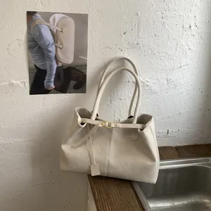 Detail of cream PU leather tote bag featuring elegant golden U-shaped buckle and handles