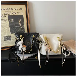 Quilted leather bucket bags with gold chain straps and horse charms displayed on magazines