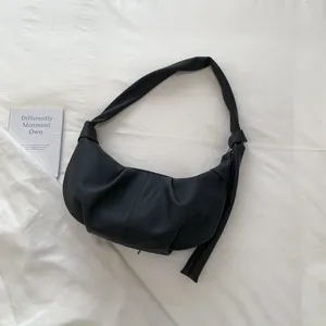 Nahaufnahme der schwarzen Crescent Bag mit Raffung, mattem Leder und geknotetem Riemen