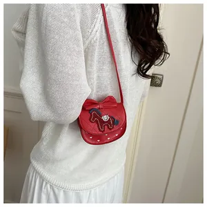 Detail van rode gewatteerde crossbodytas met strikdecoratie en paardenborduurwerk