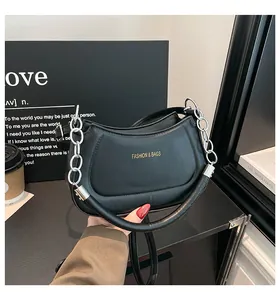 Detail einer mattschwarzen Lederhandtasche mit Goldaufschrift und Silberkette