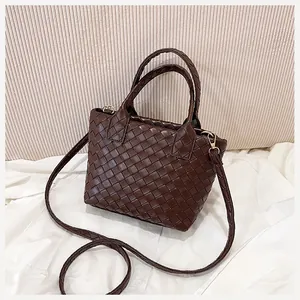 Macro detail of dark brown woven leather texture and elegant gold-tone hardware on handbag