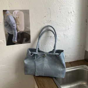 Detail of light blue suede tote bag showing minimalist metal buckle and matte texture