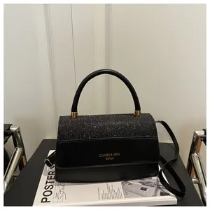 Detail of black handbag showing glittery texture and leather patchwork with gold logo