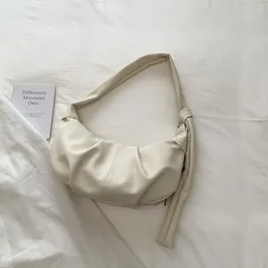 Detail der minimalistischen, cremeweißen Mondsichel-Tasche mit eleganter PU-Struktur