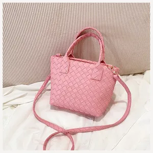 Detailed view of pink woven bucket bag with checkered pattern and dual top handles