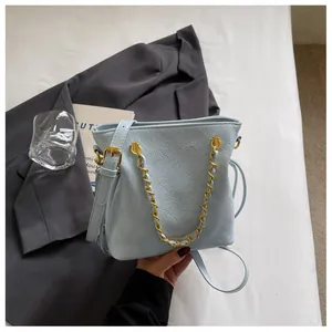 Detail of light blue quilted bucket bag with gold chain strap and leather texture