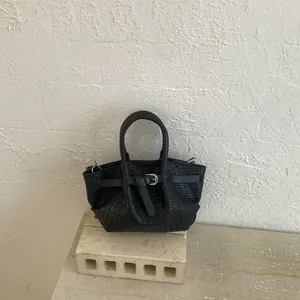 Detail of a black woven texture bucket bag featuring silver hardware and a top handle