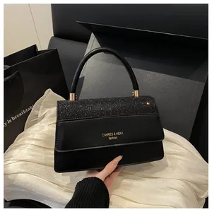 Close-up of black leather handbag with glittery flap and gold lettering in a luxury setting