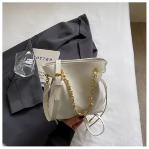 Detail of white quilted bucket bag featuring vintage texture leather and gold chain strap