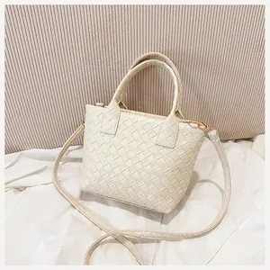Detail of cream woven tote bag showing fine texture and golden metal hardware