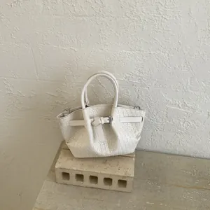 Detailed view of the woven texture and belt buckle decor on this off-white bucket bag