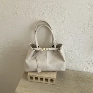 Detailed close-up of cream leather tote bag with fine stitching and metal buckle detail