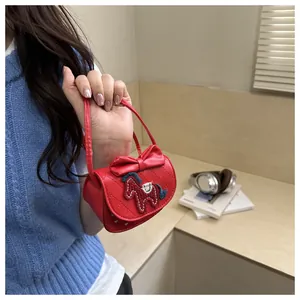 Detail van rode gewatteerde mini-tas met grote strik en kleurrijk borduursel van paard