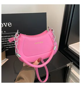 Detailansicht der pinkfarbenen matten Lederhandtasche mit Goldlogo und Silberkette