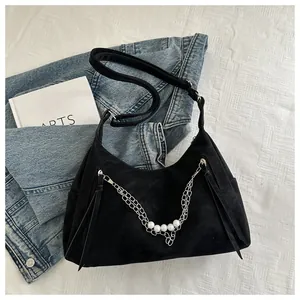 Detalle de bolso hobo negro con cadenas plateadas, perlas y cremalleras de borlas