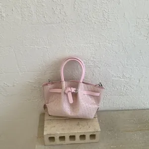 Detailed view of pale pink woven leather texture and decorative strap buckle on handbag