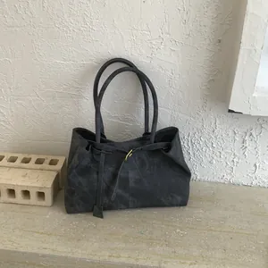 Detail of dark grey tote bag with vintage texture and golden buckle on stone background