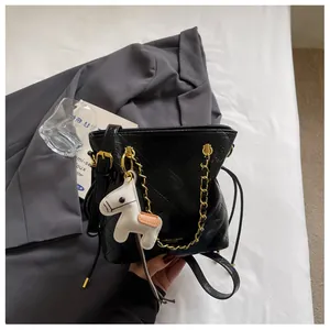 Close-up of black quilted bucket bag with gold chain and white horse charm detail