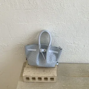 Detailed close-up of light blue woven leather tote with silver buckle and braided texture