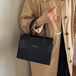 Elegante borsa a mano nera con motivo a coccodrillo e scritte dorate sulla modella