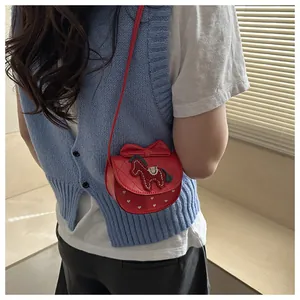 Detail van blauwe pony borduursels en rode strik op een gewatteerde crossbodytas