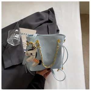 Close-up of light blue quilted bucket bag with gold chain and horse charm detail